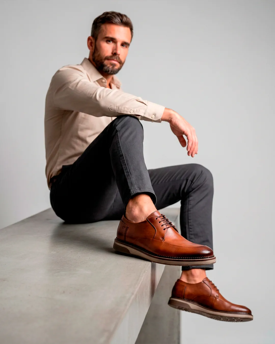Homem em estúdio minimalista usando sapatos sociais marrons