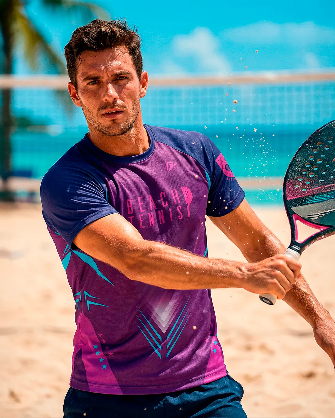 Jogador de beach tennis em ação com uniforme roxo e azul